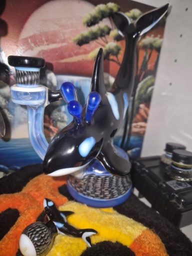 A black and white orca figurine with blue accents displayed on a patterned surface.
